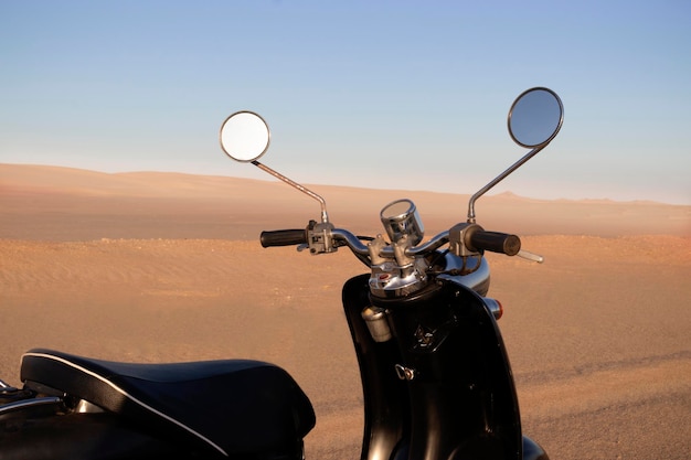 Le scooter noir rétro au coucher du soleil dans le sable doré du désert du Namib