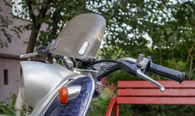 Scooter vintage ou mini moto se tient à l'extérieur. Un moyen de transport populaire. Le volant d'un vieux cyclomoteur bleu avec un siège marron.