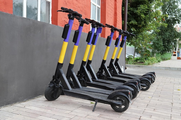 Scooters électriques pour la part du public debout à l'extérieur sur la rue de la ville Transport mobile public