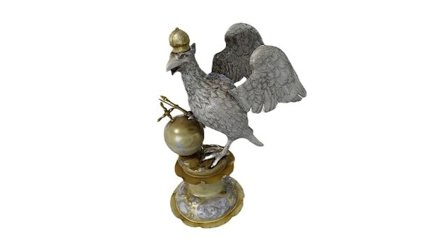 Une sculpture en bronze d'un poulet avec une boule d'or sur le dessus.