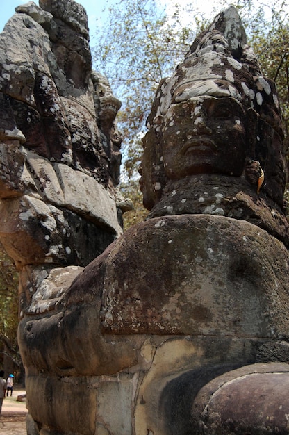 Photo sculpture sculpture figure divinité ange esprit et statue naga à l'entrée des ruines antiques du bâtiment nokor thom du pont de la porte sud dans la culture hindoue et bouddhiste aller à angkor wat à siem reap cambodge
