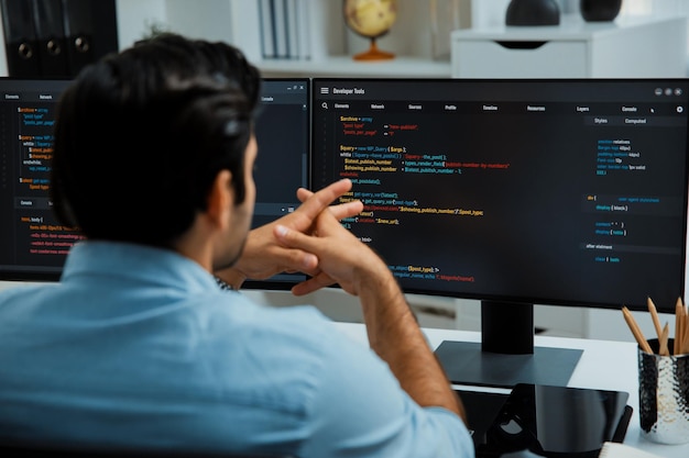 Photo se concentrant sur le développeur intelligent, travaillant sur le codage sur deux écrans d'ordinateur, je suppose.
