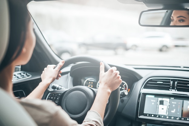 Se concentrer sur la conduite. Vue arrière d'une jeune femme séduisante en tenue décontractée regardant sur la route en conduisant une voiture