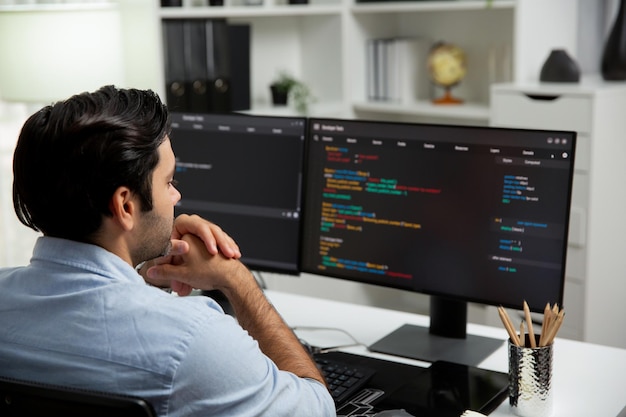 Se concentrer sur le développeur informatique intelligent travaillant sur le codage sur deux écrans de PC Surmise