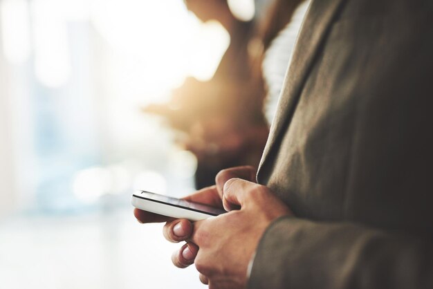 Se connecter avec plusieurs personnes partageant les mêmes idées Photo d'un homme d'affaires utilisant son téléphone portable avec des collègues flous en arrière-plan