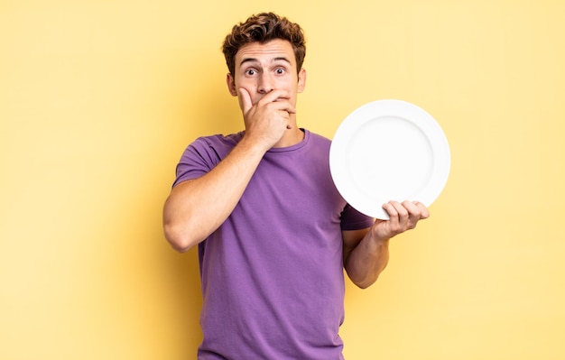 Se couvrir la bouche avec les mains avec une expression choquée et surprise, garder un secret ou dire oups. concept d'assiette vide