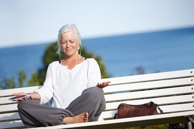 Se détendre avec de la musique tranquille Photo d'une femme mûre écoutant de la musique tout en faisant un exercice de relaxation à l'extérieur