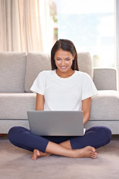 Se détendre avec ses amis en ligne Photo d'une belle jeune femme utilisant un ordinateur portable à la maison