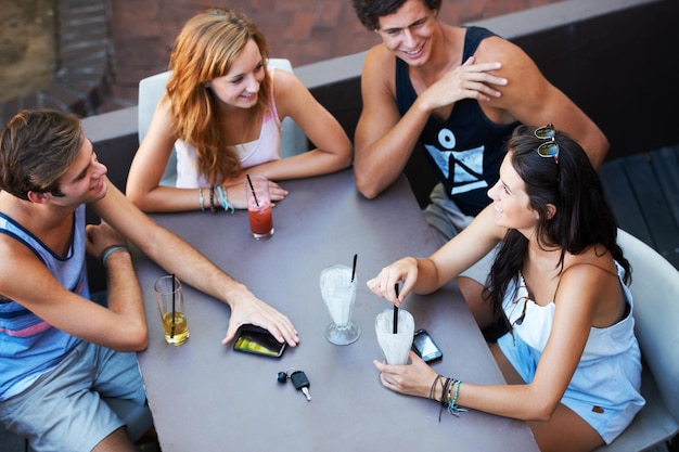 Se détendre avec tout le gang Groupe d'adolescents dégustant des milkshakes et des boissons dans un restaurant en plein air à angle élevé