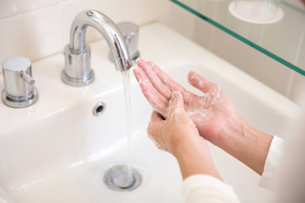 Se laver les mains avec du savon sous l'eau courante, mains de femme