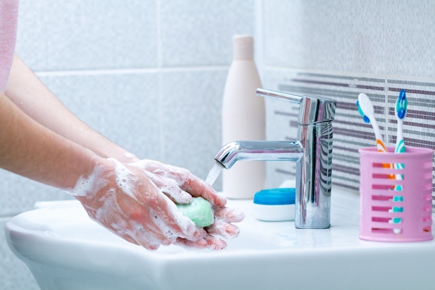 Se laver les mains avec du savon sous le robinet avec de l'eau dans la salle de bain. Hygiène, protection et prévention contre les virus et les bactéries