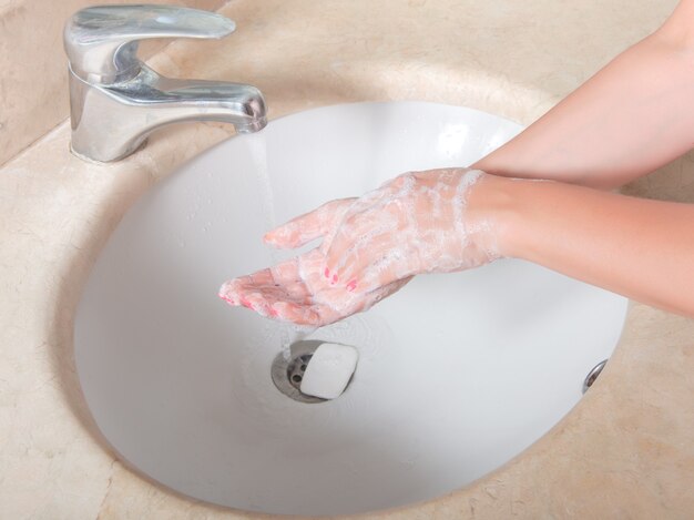 Se laver les mains avec du savon sous le robinet