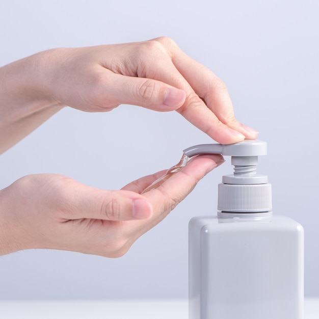 Se laver les mains. Jeune femme asiatique utilisant du savon liquide pour se laver les mains, concept d'hygiène pour arrêter la propagation du coronavirus isolé sur fond blanc gris, gros plan.