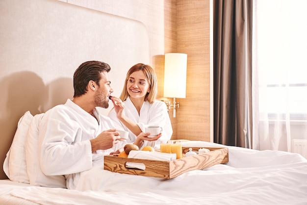 Se nourrir les uns les autres. Un couple mange ensemble dans un lit de chambre d'hôtel. Histoire d'amour.