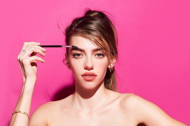 Se peigne les sourcils avec une brosse dans un salon de beauté femme avec de longs cils et des sourcils épais femme por