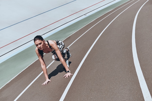 se pousser à la limite. vue de dessus de la jeune femme en vêtements de sport debout sur la ligne de départ