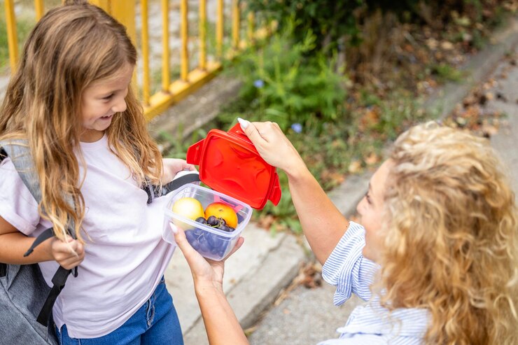 Se préparer pour le premier jour d'école Mère donnant à sa fille des collations pour l'école