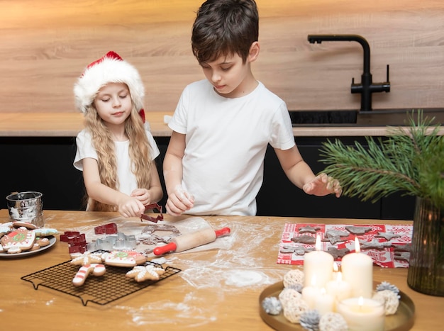 Se préparer pour les vacances de Noël. Enfants - un garçon et une fille préparent du pain d'épice dans la cuisine
