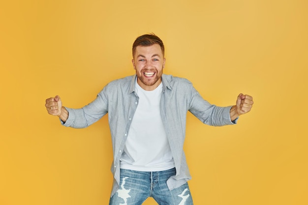 Se sent bien Jeune homme en vêtements décontractés debout à l'intérieur dans le studio