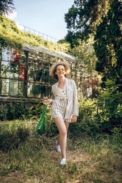 Se sentir bien. Jeune femme aux cheveux bouclés se sentir bien sur une journée ensoleillée