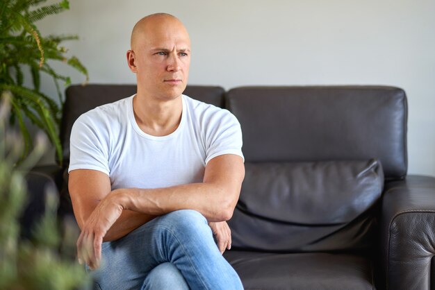 Photo se sentir déprimé. jeune homme désespéré assis sur le canapé à la maison.