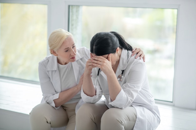 Se sentir déprimé. Médecin brune à la déprimée, son collègue à la préoccupation