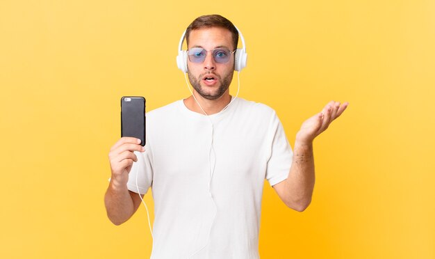 Se sentir extrêmement choqué et surpris, écouter de la musique avec des écouteurs et un smartphone