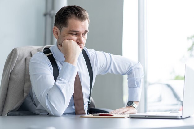 Se sentir fatigué. Jeune bel homme frustré qui a l'air épuisé alors qu'il est assis sur son lieu de travail.