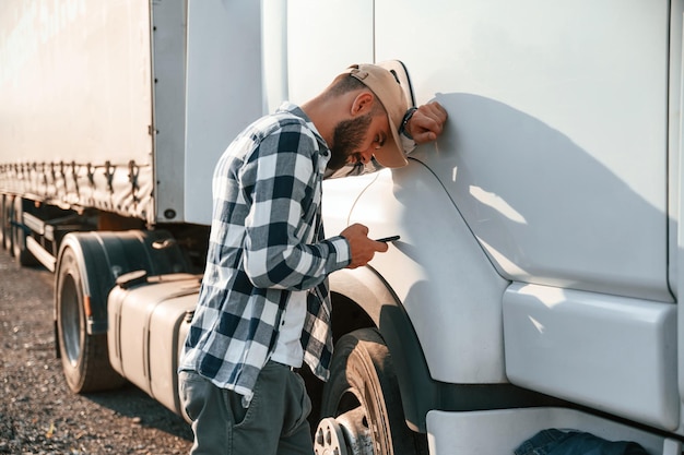 Se sentir fatigué Utiliser un smartphone Un jeune chauffeur de camion est avec son véhicule pendant la journée