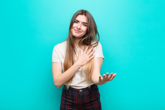 se sentir heureux et amoureux, souriant avec une main à côté du cœur et l'autre tendue vers l'avant