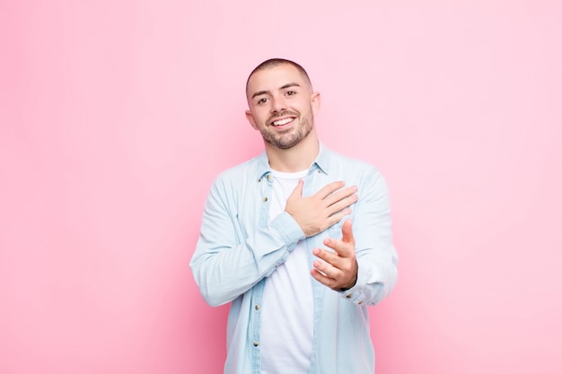 se sentir heureux et amoureux, souriant avec une main à côté du cœur et l'autre tendue vers l'avant