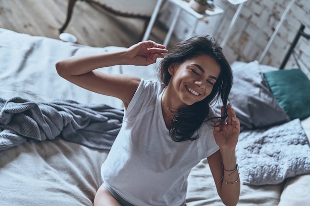 Se sentir heureux et rafraîchi. Vue de dessus de la belle jeune femme s'étirant et souriant