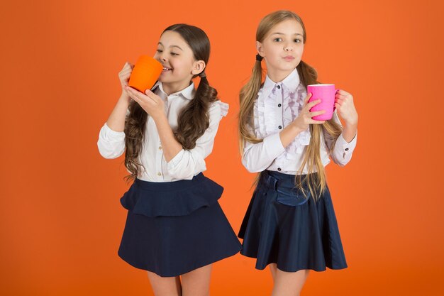 Se sentir plus alerte Écolières mignonnes tenant des tasses à thé Petits enfants buvant du thé ou du café le matin Écoliers prenant leur petit déjeuner le matin Petites filles appréciant leur petit déjeuner à l'école