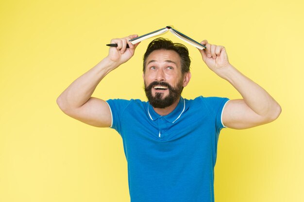 Se sentir en sécurité avec le plan Un homme barbu mature tient un bloc-notes comme toit Vérifier ce qui est fait Plan quotidien Développer des habitudes et établir une routine Plan de tâches Liste de contrôle quotidienne à faire et à faire Plan utile