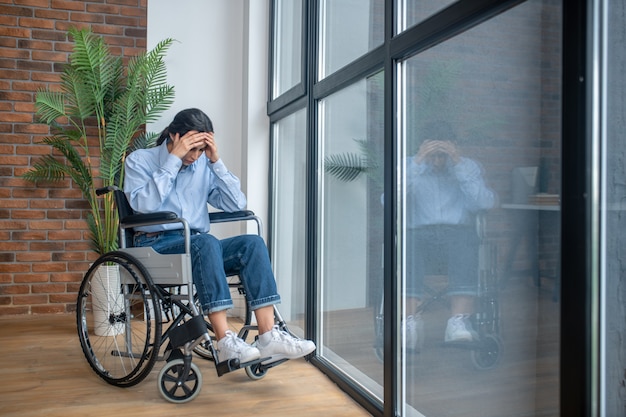 Se sentir seul. Une jeune fille en fauteuil roulant à l'air frustrée et contrariée