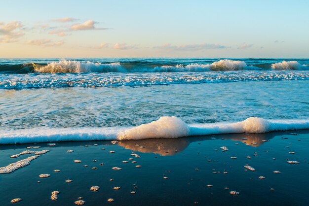 Seafoam sur le sable de la plage avec un paysage de ciel bleu clair