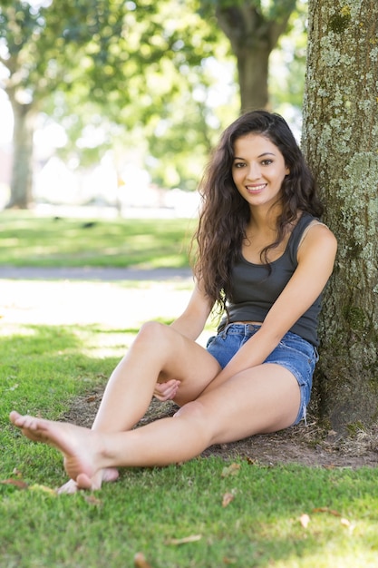 Séance de brunette souriante décontractée, appuyé contre l&#39;arbre