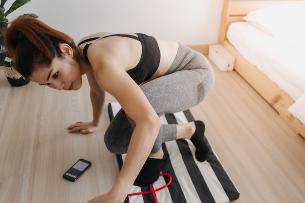 Séance d'entraînement de femme dans la chambre avec le téléphone portable