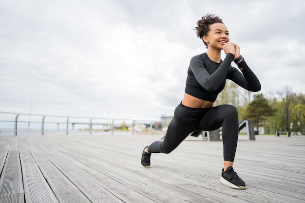 Séance d'entraînement millénaire de femme athlétique confiante dans la rue exercices actifs dans les vêtements de sport