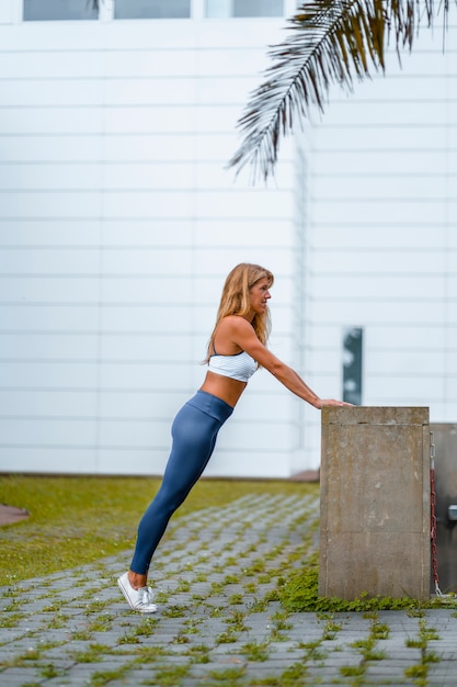 Séance de fitness et de yoga avec une jeune instructrice blonde caucasienne vêtue d'une tenue décontractée avec Maya bleue et un t-shirt blanc. Effectuer des étirements avant de commencer l'exercice