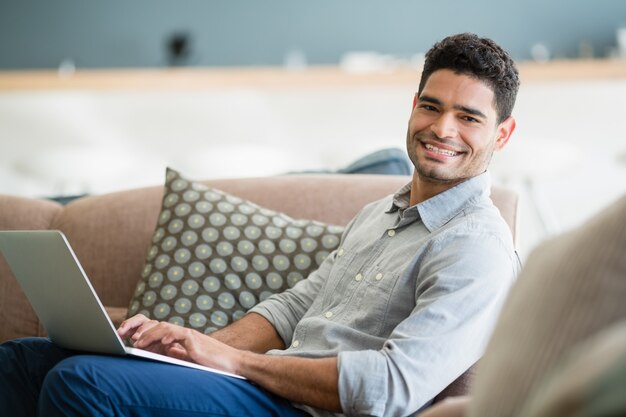 Séance homme, sur, sofa, et, portable utilisation, dans, salle de séjour, chez soi