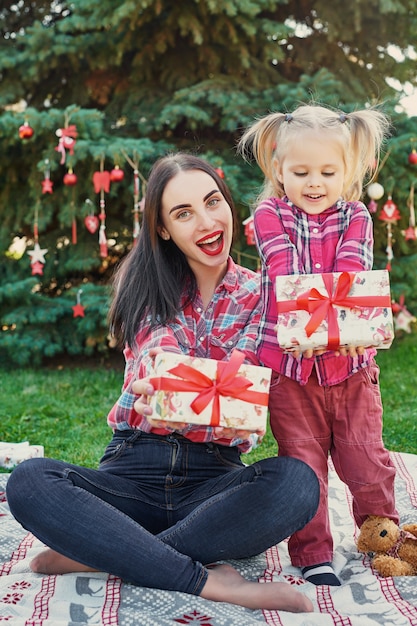 Séance photo en famille avec le Nouvel An en juillet près de l'arbre de Noël avec des cadeaux dans le parc