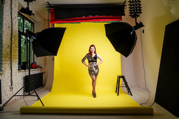 Séance photo en studio d'une fille en robe noire sur fond jaune