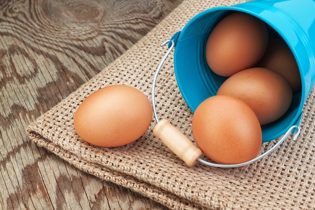 Seau bleu et oeufs de Pâques éparpillés sur un sac.