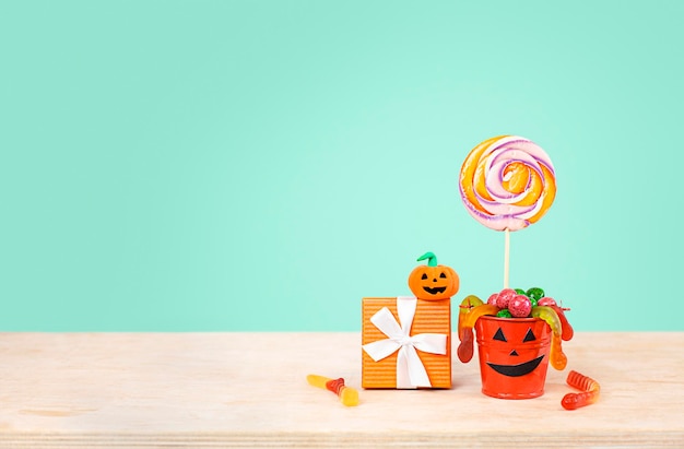 seau avec bonbons et marmelade avec une boîte-cadeau sur fond bleu. notion d'halloween