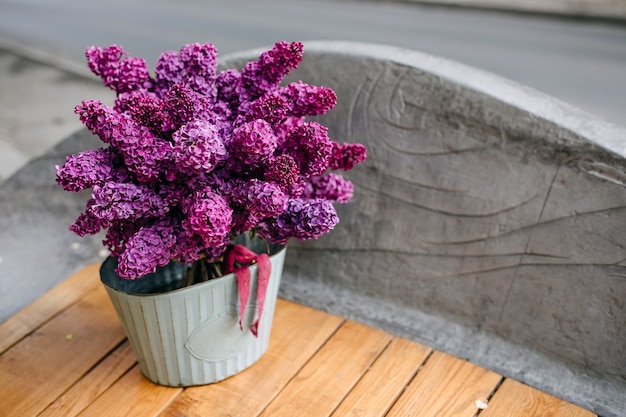 Seau avec un bouquet de fleurs lilas violet sur un banc en bois