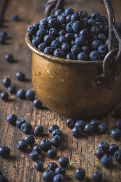 Seau en cuivre avec des bleuets de forêt sauvage biologique sur une table en bois rustique