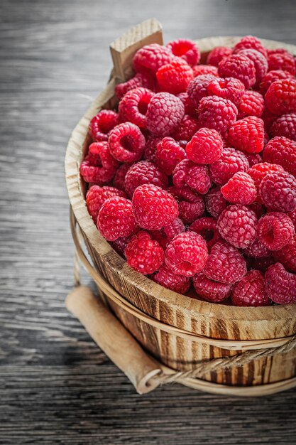 Seau de framboises fraîches sur planche de bois