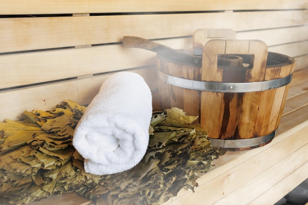 Seau louche balai et serviette blanche dans un sauna Accessoires de sauna classiques