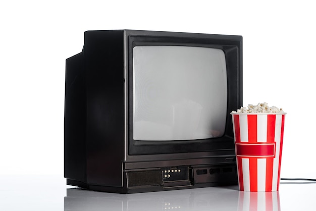 Seau avec pop-corn près de la télévision vintage sur le concept d'évolution blanche